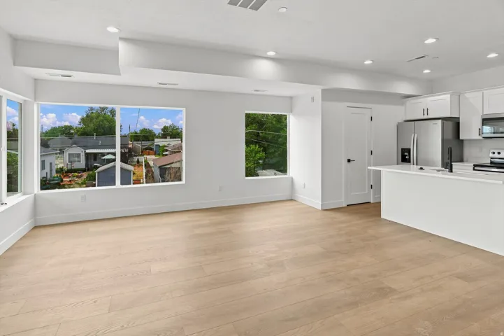 Open-concept living area with light wood-finish flooring, recessed lighting, and expansive windows