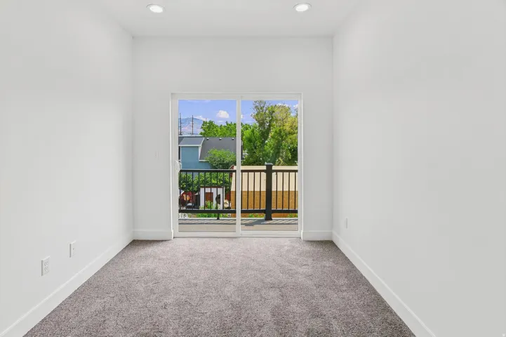 Room featuring recessed lighting, a sliding glass door, and a private balcony with a black metal railing