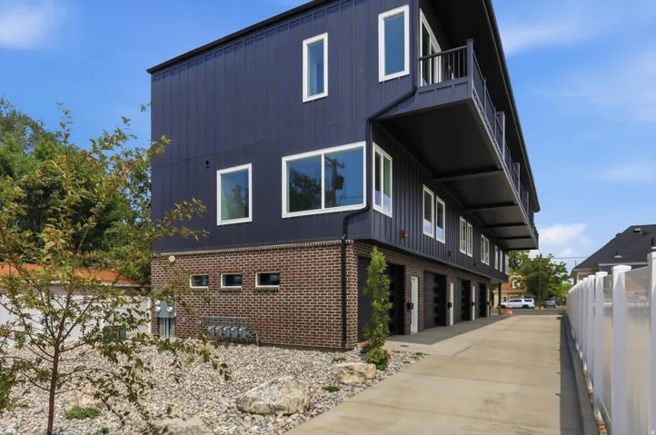 Modern multi-story building featuring dark vertical siding and brickwork