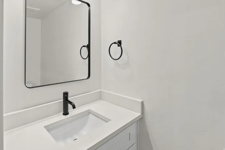 Bathroom vanity featuring a matte black faucet, an integrated sink, and a light-toned countertop