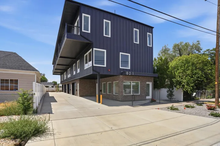 Modern multi-story building featuring dark vertical siding and a partial brick facade