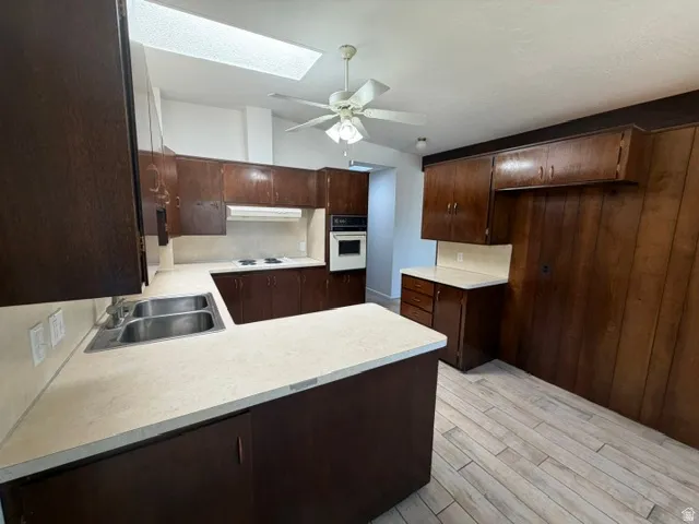 Kitchen featuring extensive wood-finish cabinetry, light-toned countertops, and a double basin stainless steel sink