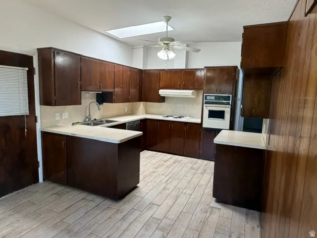 Kitchen featuring extensive wood cabinetry, light-toned countertops, and wood-finish flooring