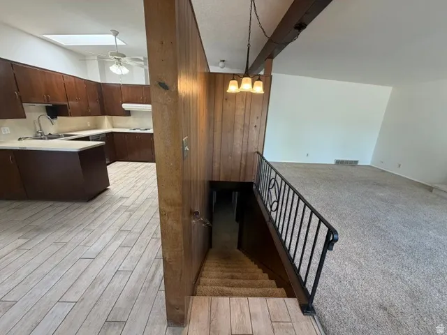 Open-concept kitchen featuring wood-finish cabinetry, light-toned countertops, and a skylight