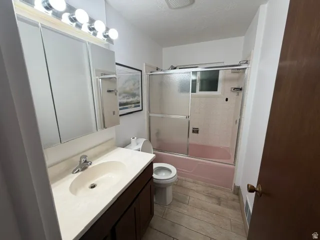 Bathroom featuring a dark wood-finish vanity with an integrated sink, a chrome faucet, and a wall-mounted mirrored medicine cabinet