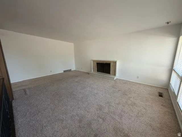 Spacious interior room featuring light-colored carpeting and white walls