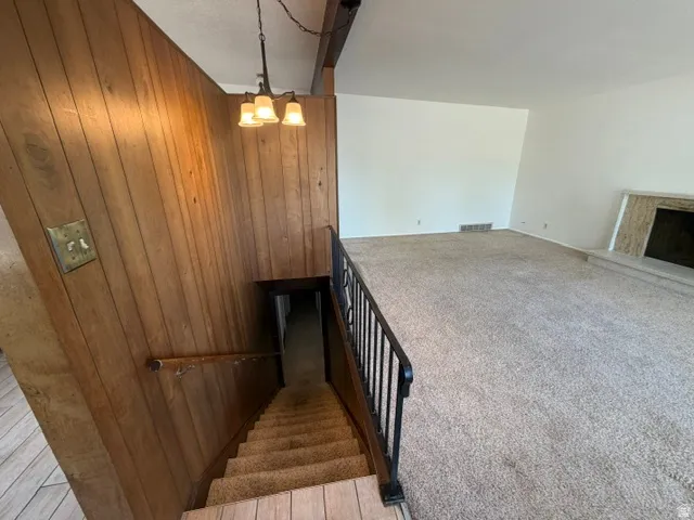Lower-level stairwell with wood-paneled walls and a black metal handrail