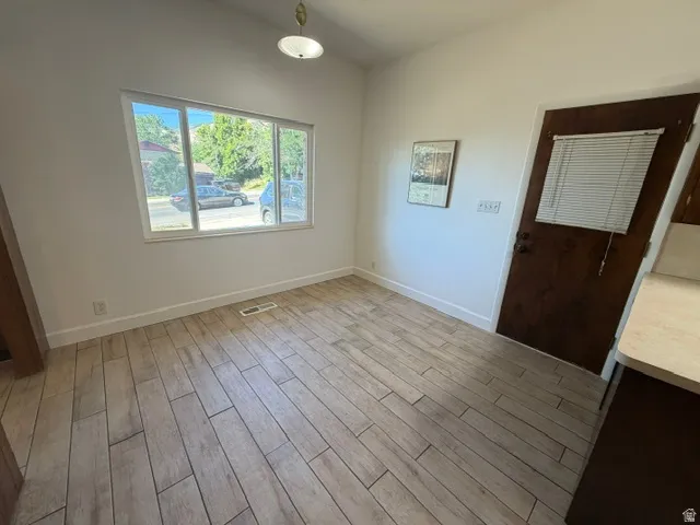 Bright interior space featuring wood-look plank flooring, white baseboards, and a large window
