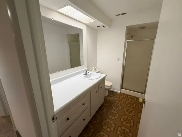 Bathroom featuring a vanity with integrated sink, expansive wall mirror, and a shower with a sliding glass enclosure