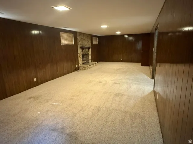 Spacious room featuring wood paneling walls and neutral-toned carpeting