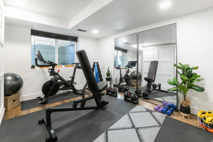Dedicated fitness space featuring ample natural light from a large window, recessed lighting, and wall-mounted mirrors