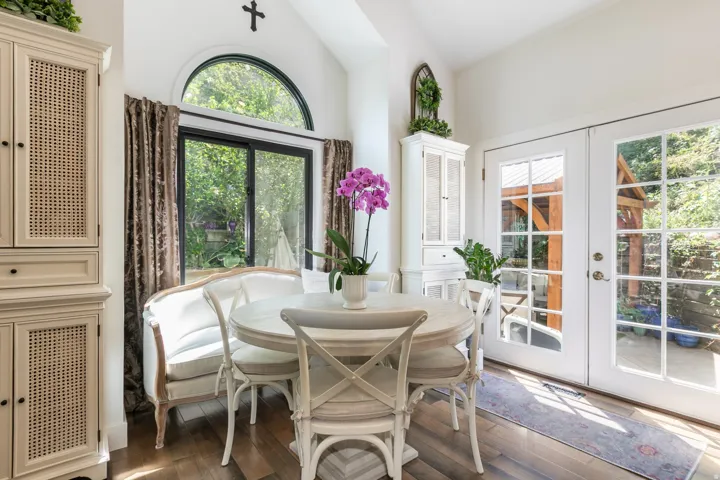 Dining area featuring wood-finish flooring, a vaulted ceiling, and dual French doors opening to an exterior structure