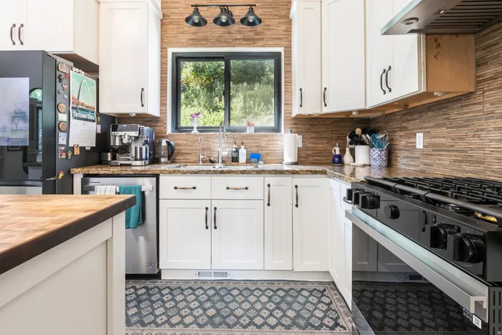 Contemporary kitchen featuring white cabinetry, a stone-finish countertop, and a stainless steel dishwasher