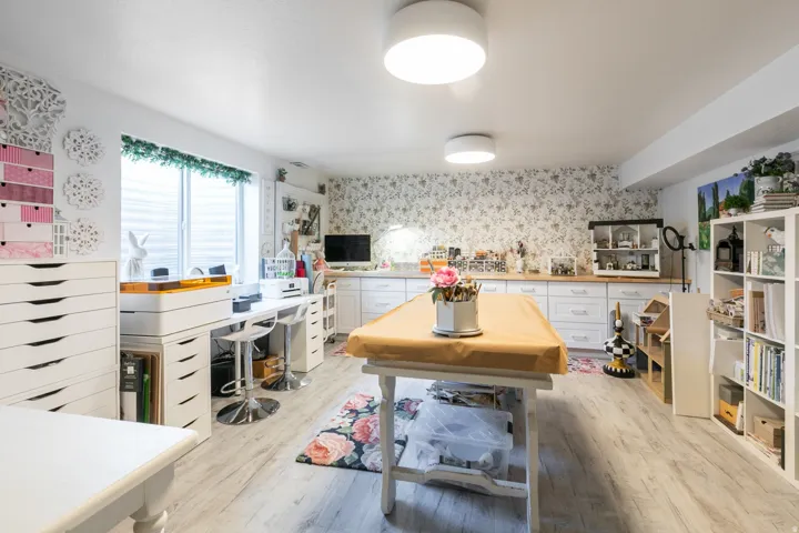 Spacious room featuring wood-finish flooring, white built-in cabinetry with wood countertops, and a window with horizontal blinds