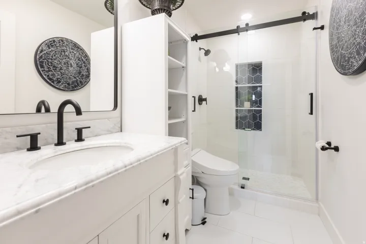 White vanity with a marble countertop, black fixtures, and an undermount sink