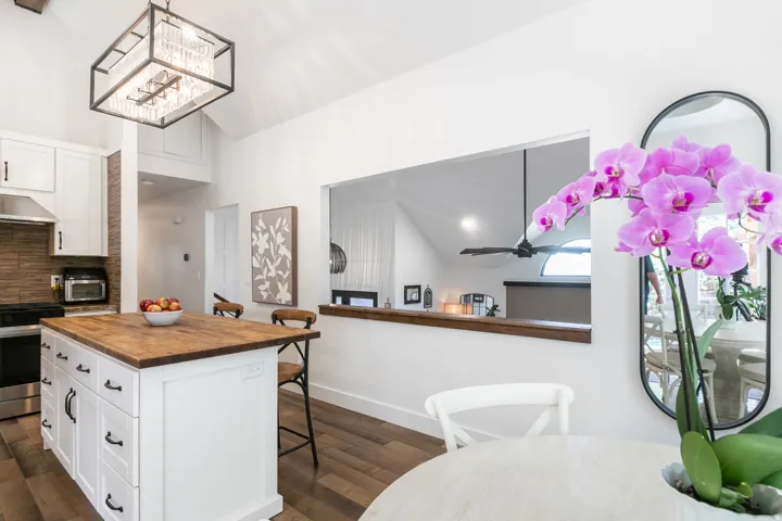 Kitchen with vaulted ceiling, wood-finish flooring, white cabinetry, a wood butcher block island, and a textured backsplash