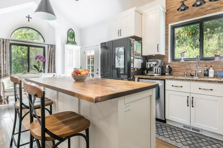 Kitchen featuring a wooden island countertop with seating, white shaker cabinetry, stainless steel appliances, and a tiled backsplash