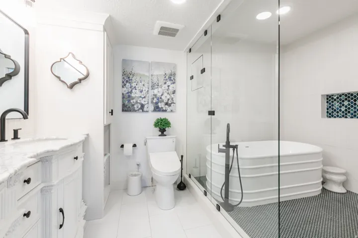 Contemporary bathroom featuring a freestanding soaking tub within a glass-enclosed shower, complemented by a mosaic tile shower floor and a built-in shower niche
