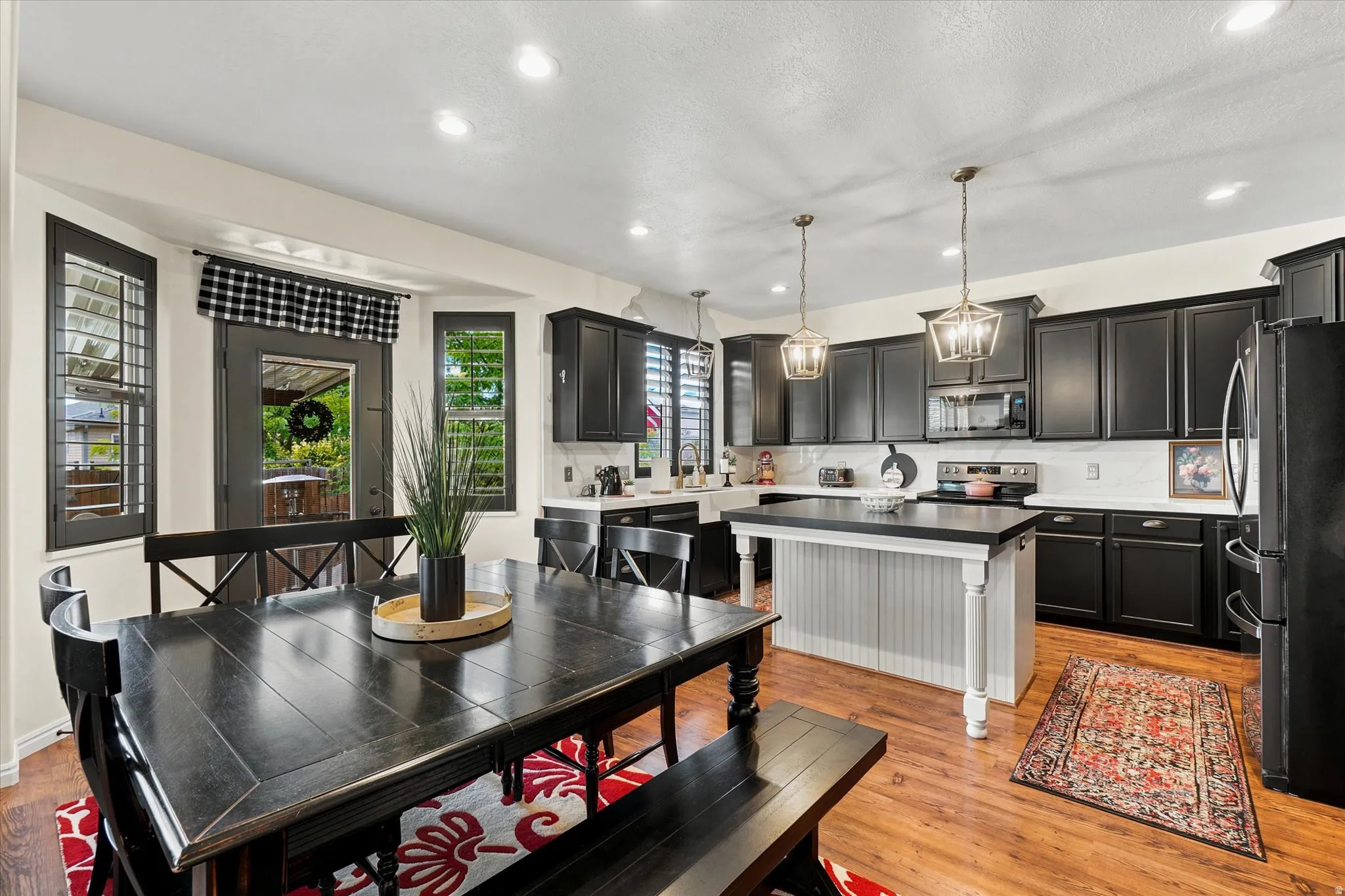 Open-concept kitchen and dining area featuring dark wood-finish flooring, recessed lighting, and a kitchen island with beadboard paneling