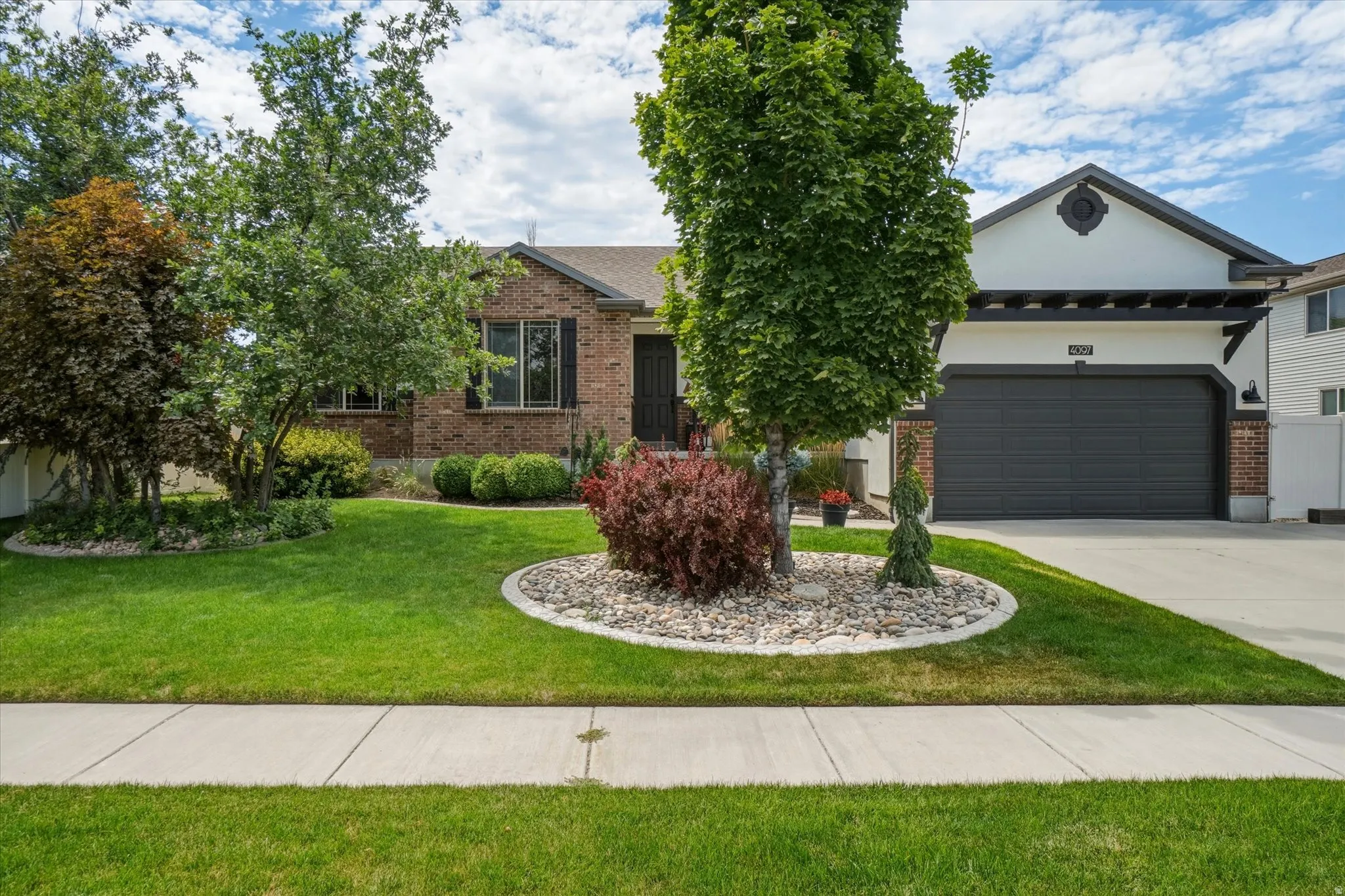 Brick and stucco exterior with an attached garage, featuring a dark garage door and a decorative trellis