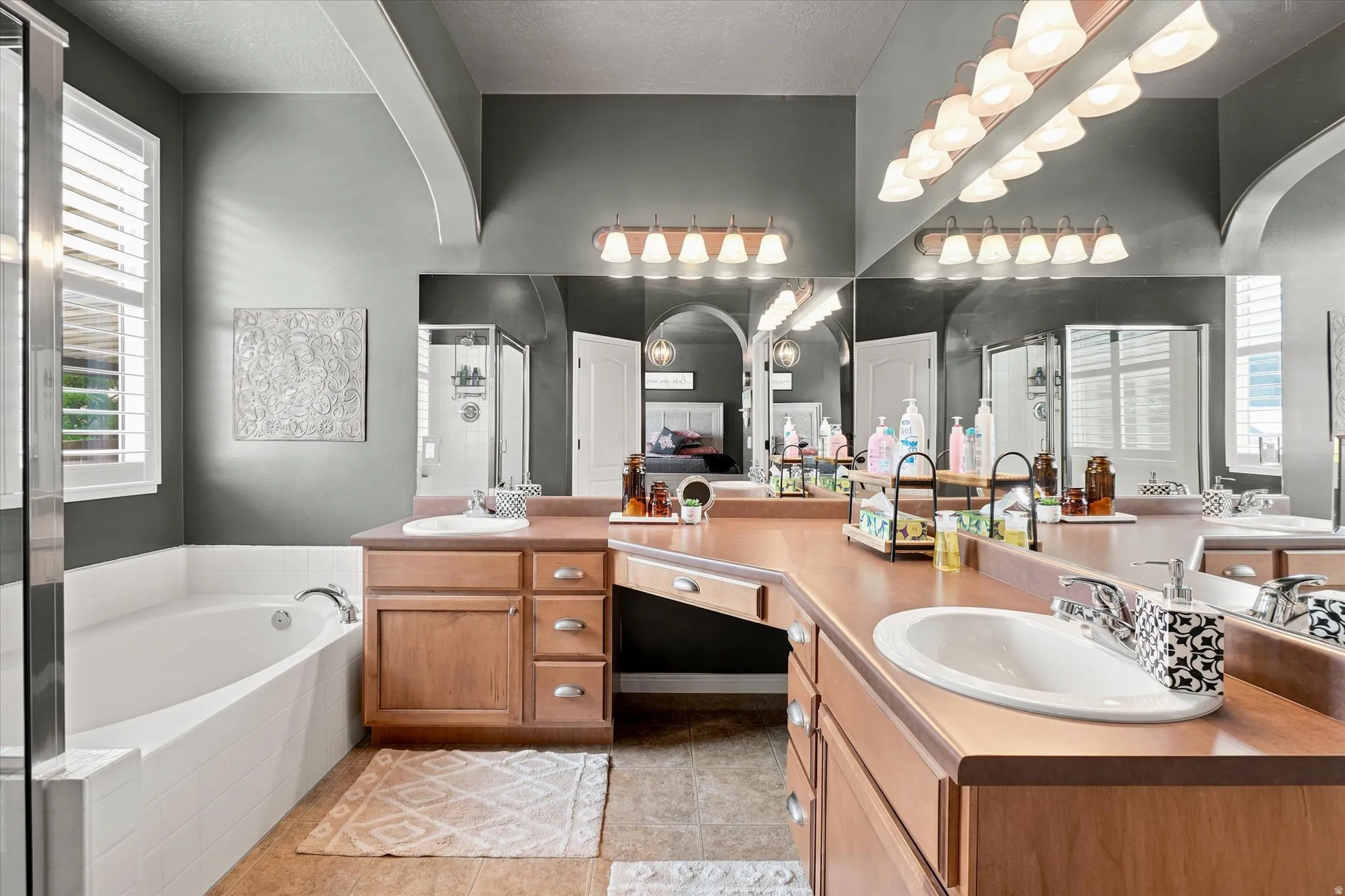 Bathroom featuring a built-in soaking tub, dual vanity with wood cabinetry, and a walk-in shower with glass enclosure