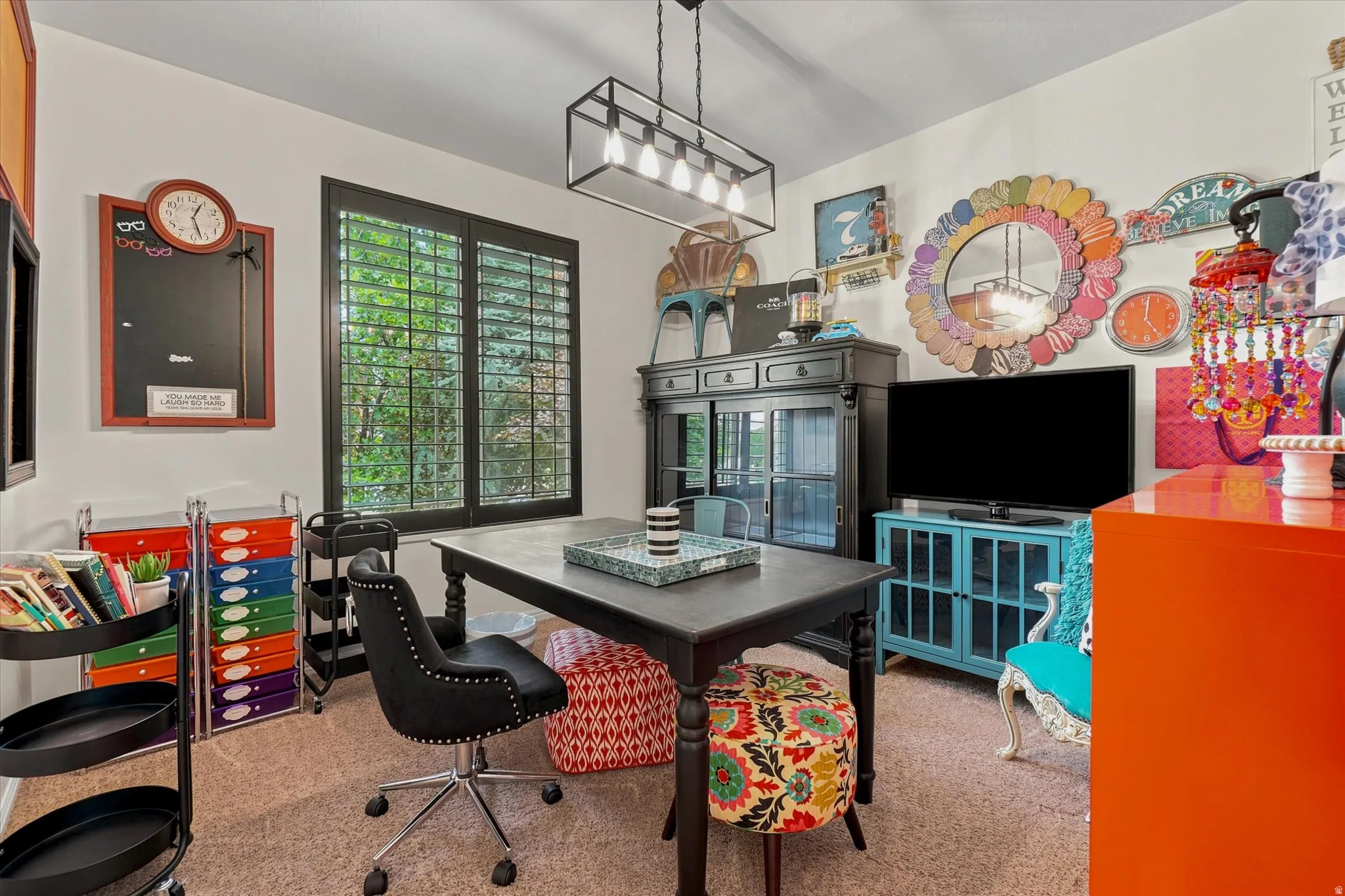 Multipurpose room featuring black framed windows with plantation shutters, a linear pendant light fixture, and neutral carpet flooring