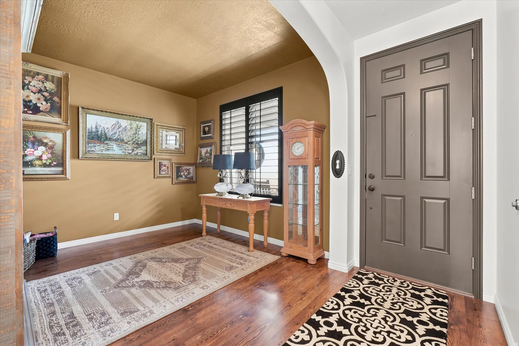 Entryway featuring wood-finish flooring, a paneled front door, and an arched doorway