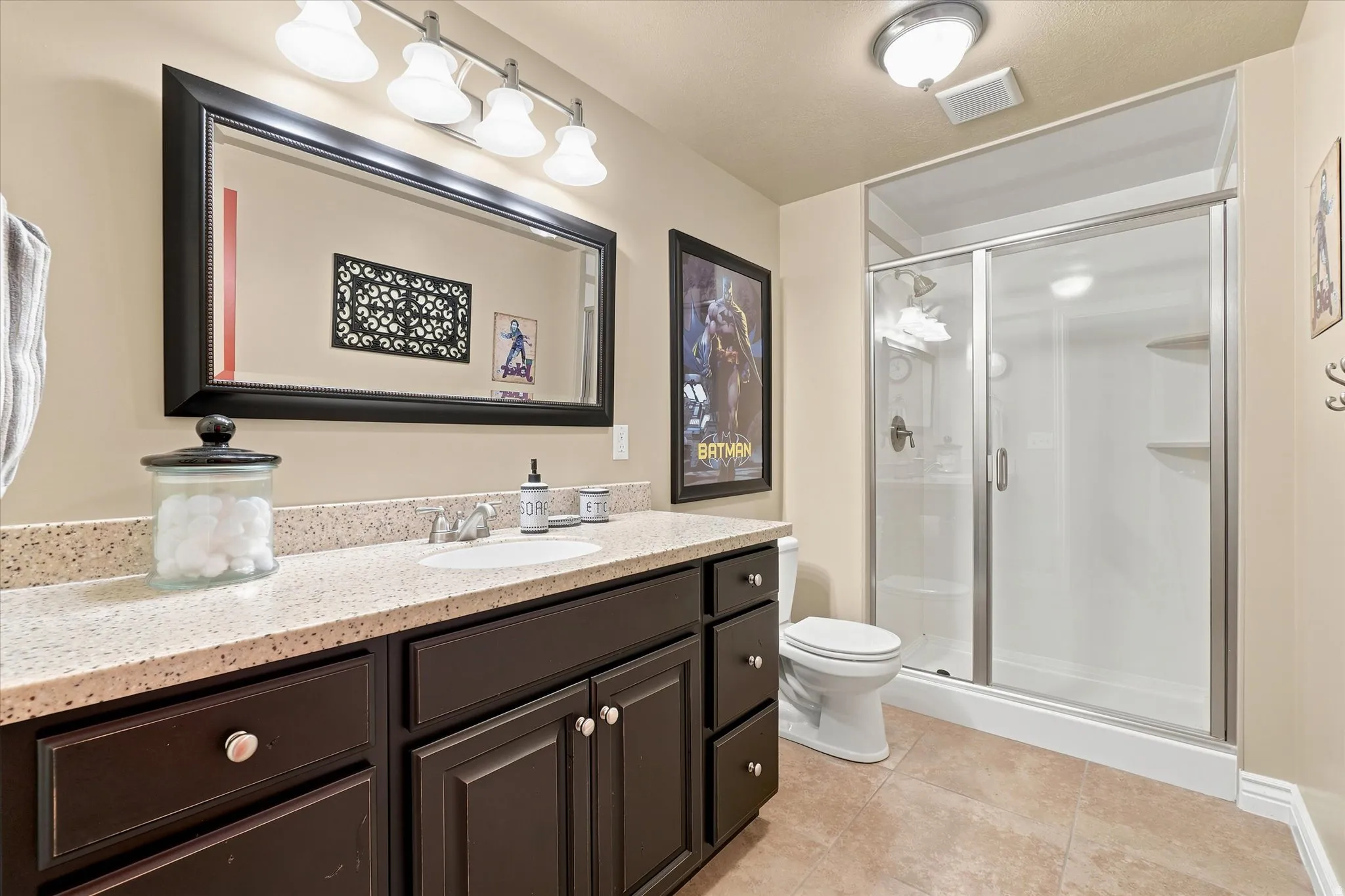 Bathroom featuring a vanity with a light-toned countertop, a single undermount sink, and dark wood-finish cabinetry