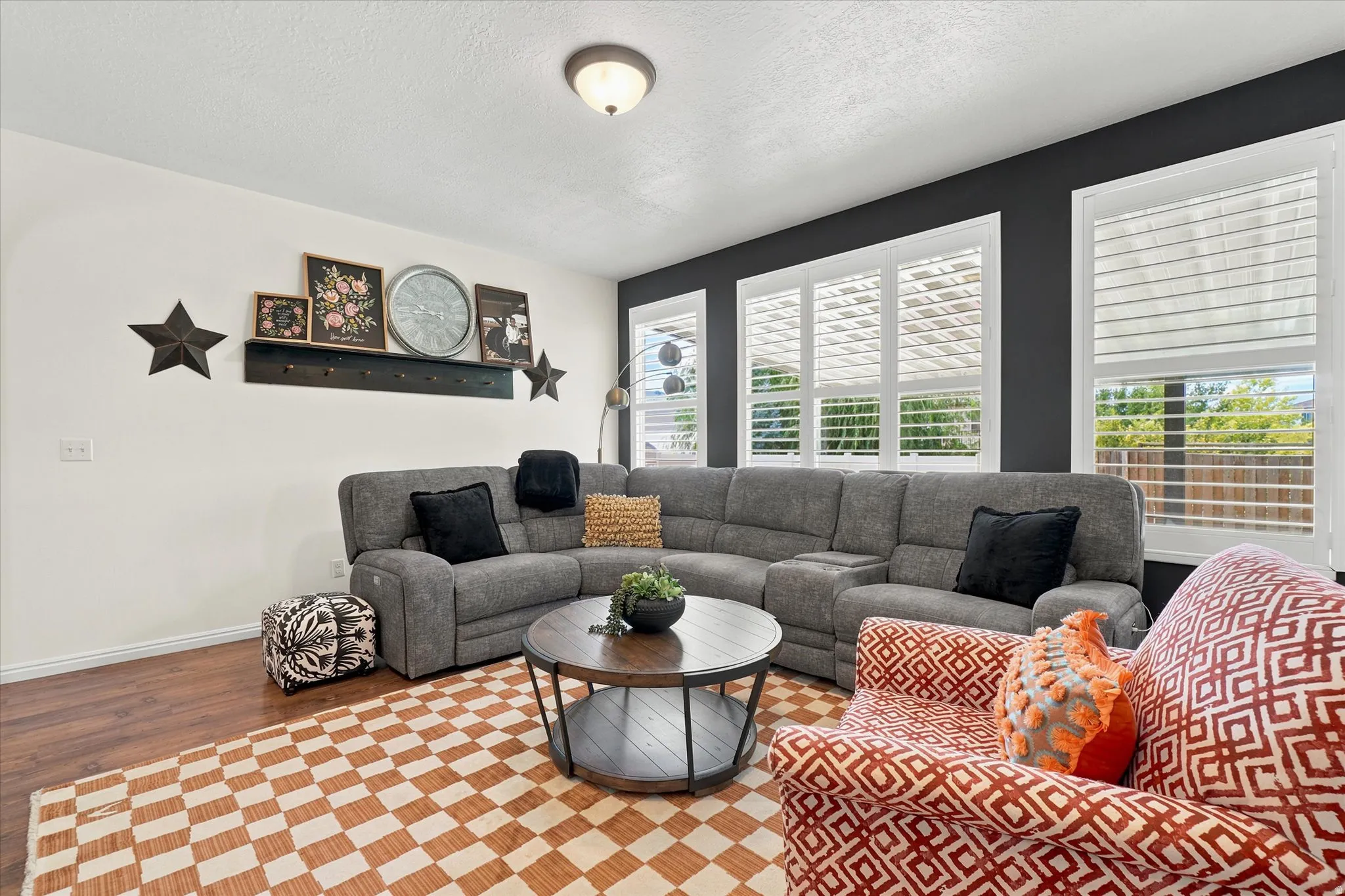 Living area featuring wood-finish flooring, white baseboards, and a combination of white and dark accent walls