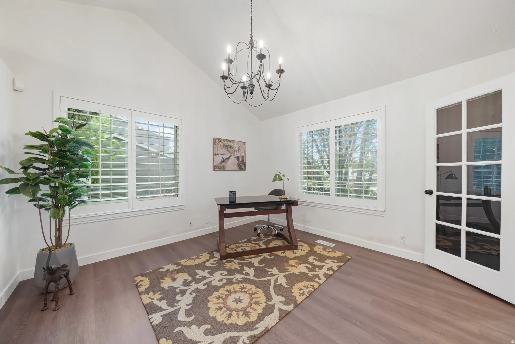 Vaulted ceiling room featuring wood-finish flooring and a multi-pane glass door