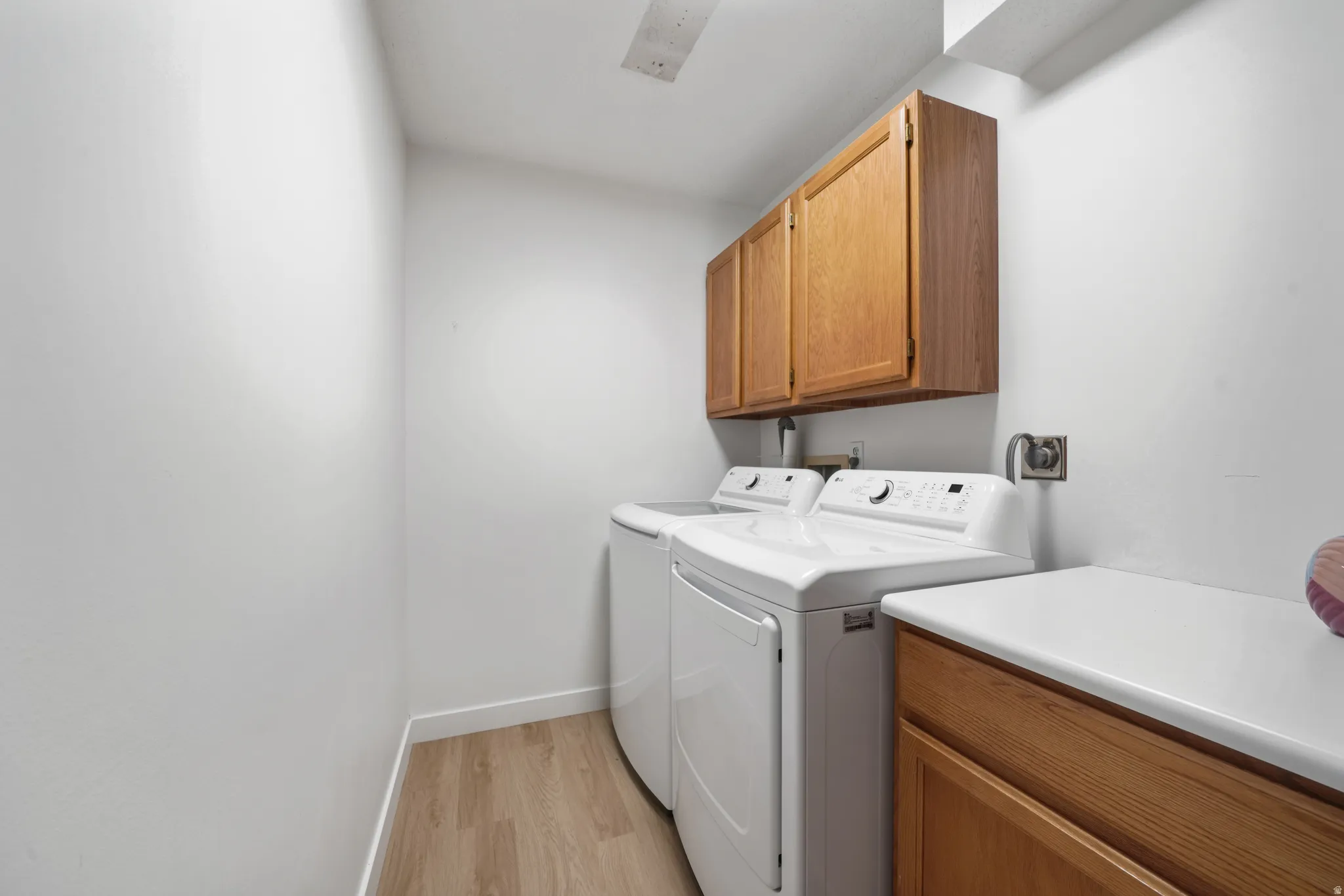 Dedicated laundry area featuring wood-finish flooring, white walls, and wood cabinetry for storage