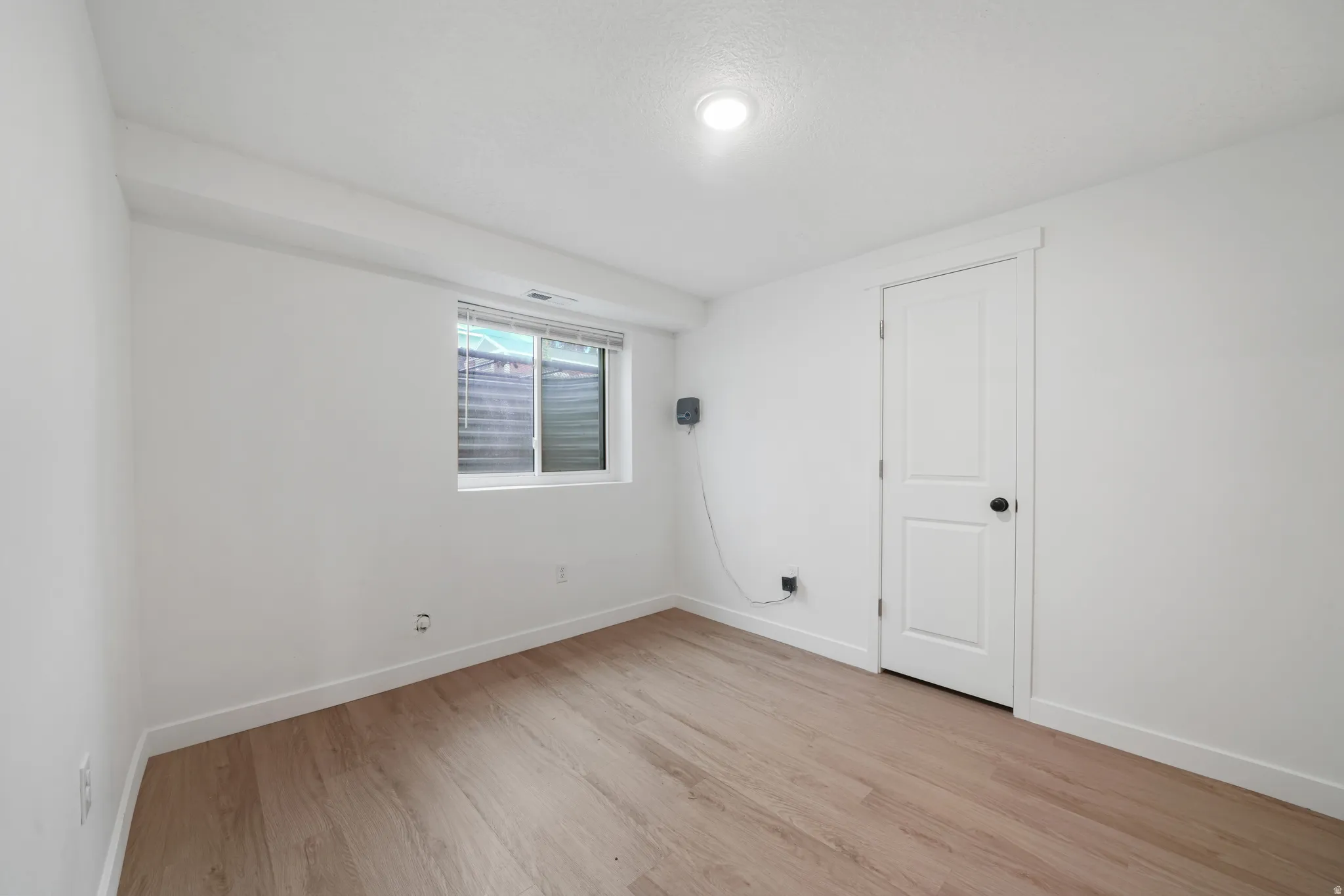 Interior room with wood-finish flooring, white walls, and a recessed ceiling light