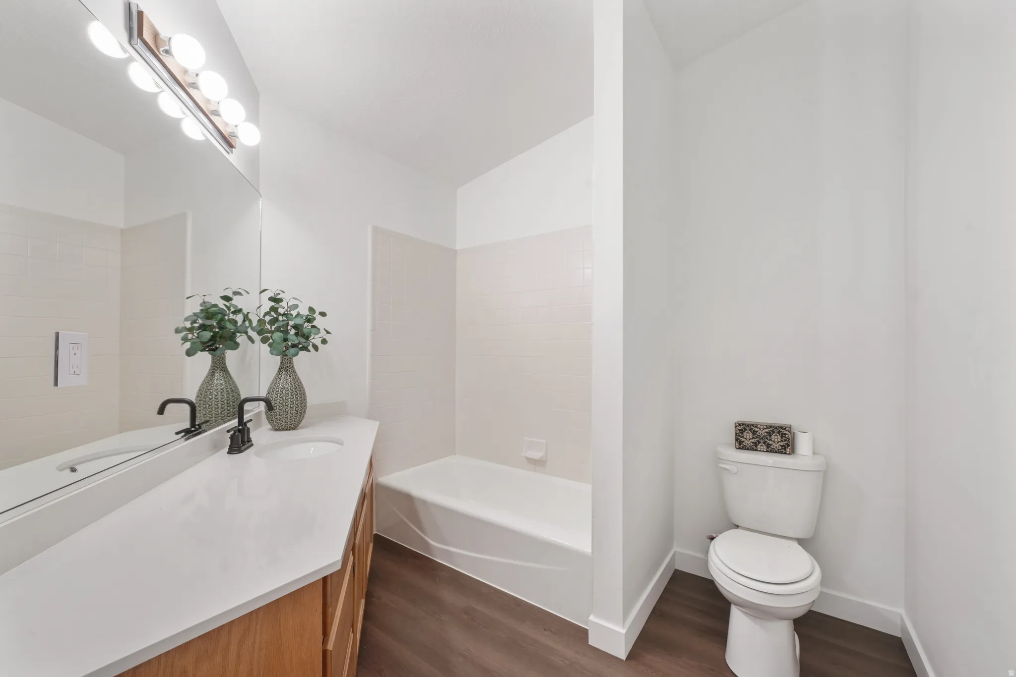 Bathroom featuring a light wood-finish vanity with a white countertop and dual sinks, complemented by matte black faucets