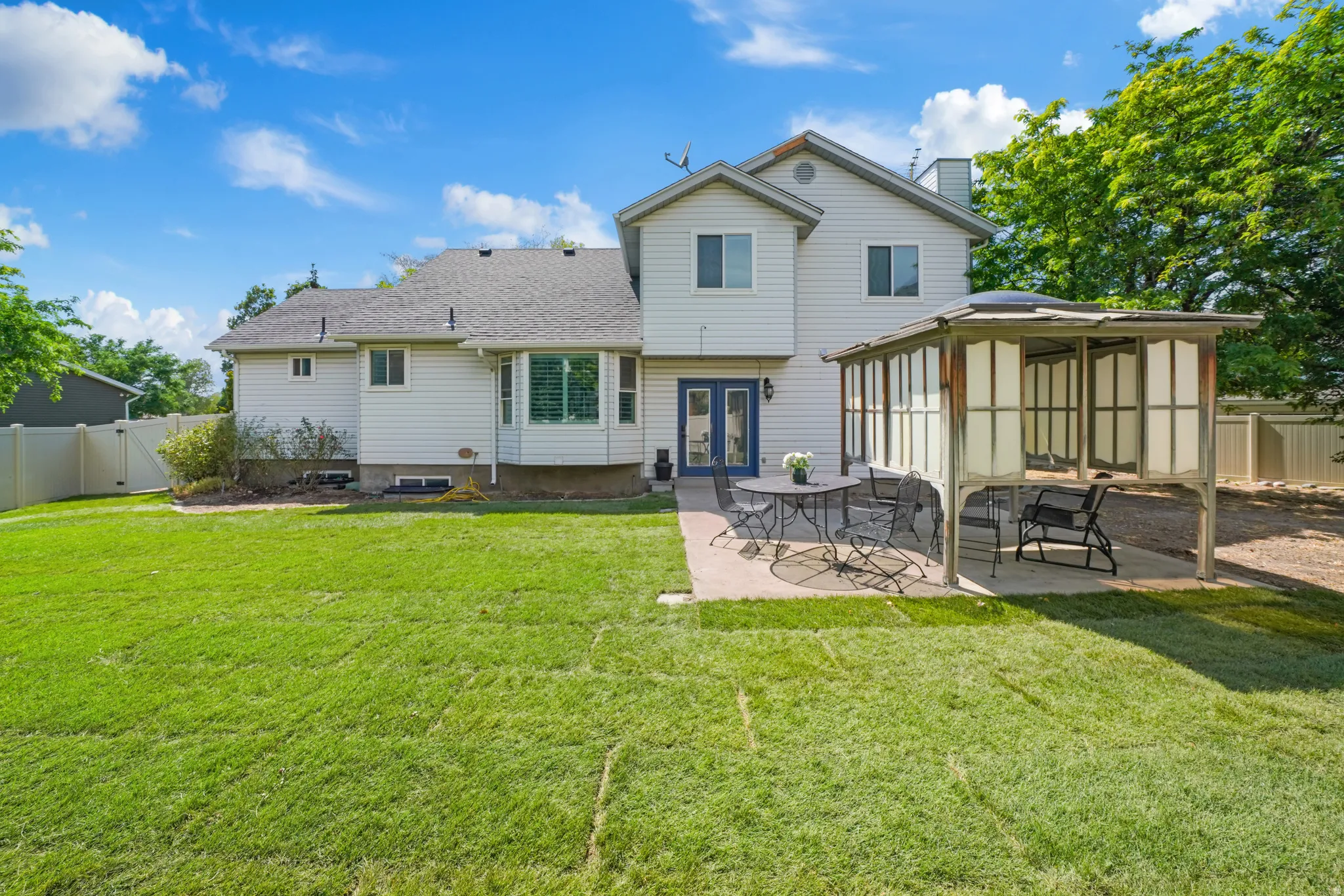 Expansive backyard featuring a manicured lawn, concrete patio, and a covered pergola