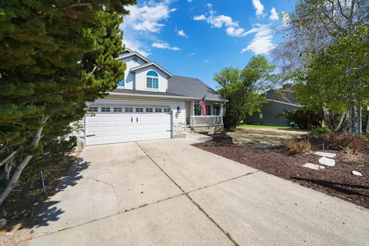 Two-story residence featuring light-colored siding, a dark roof, and a two-car garage with a concrete driveway
