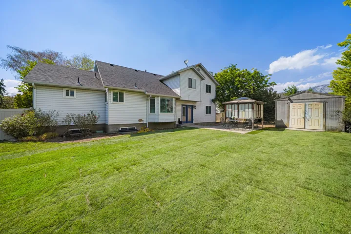 Expansive green lawn with a two-story residence featuring light-colored siding and a dark shingle roof