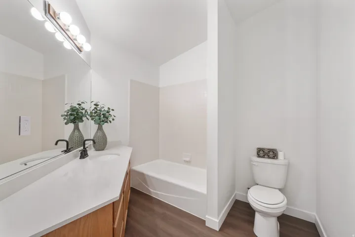 Bathroom featuring a light wood-finish vanity with a white countertop and dual sinks, complemented by matte black faucets