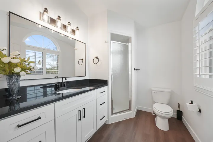 Bathroom featuring a single vanity with dark countertop, white cabinetry, and matte black hardware