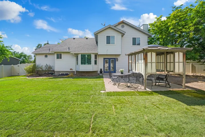 Expansive backyard featuring a manicured lawn, concrete patio, and a covered pergola