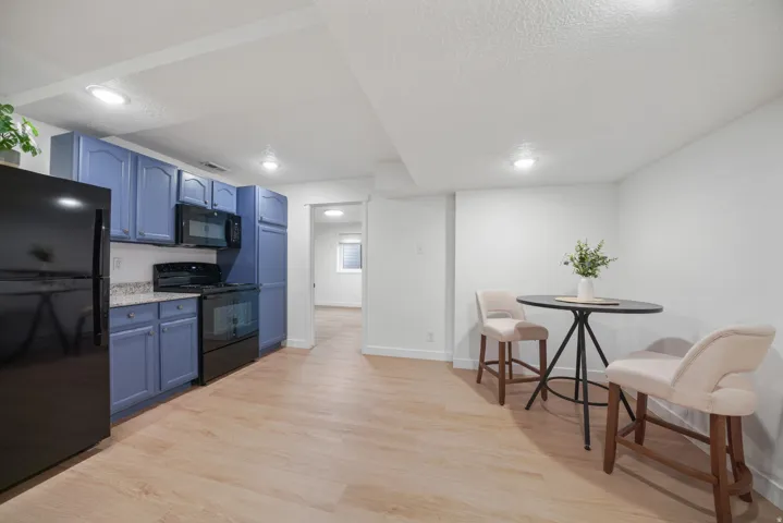 Kitchen area featuring light wood-finish flooring, blue cabinetry, stone-finish countertops, and recessed lighting