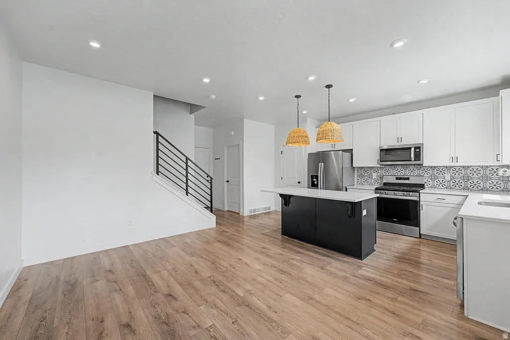 Open-concept living space featuring wood-finish flooring, recessed lighting, and a modern kitchen