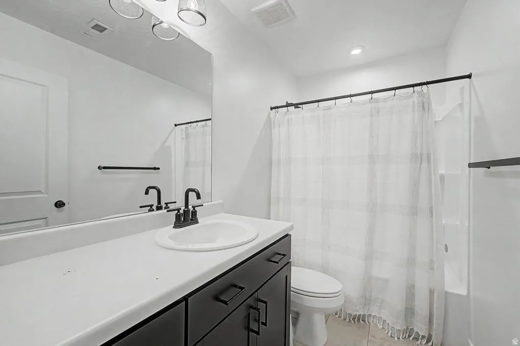 Bathroom featuring a single vanity with a white countertop, dark cabinetry, and black hardware