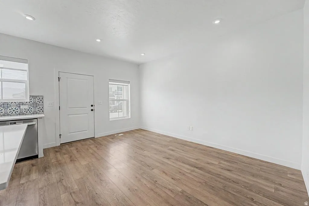 Spacious interior featuring wood-finish flooring, recessed lighting, and a white paneled door