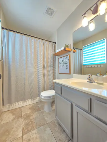 Full bathroom featuring a white toilet, tiled flooring, and a light gray vanity with a built-in sink