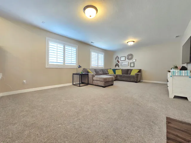 Spacious room featuring neutral carpeting, light-toned walls, and white plantation shutters on multiple windows