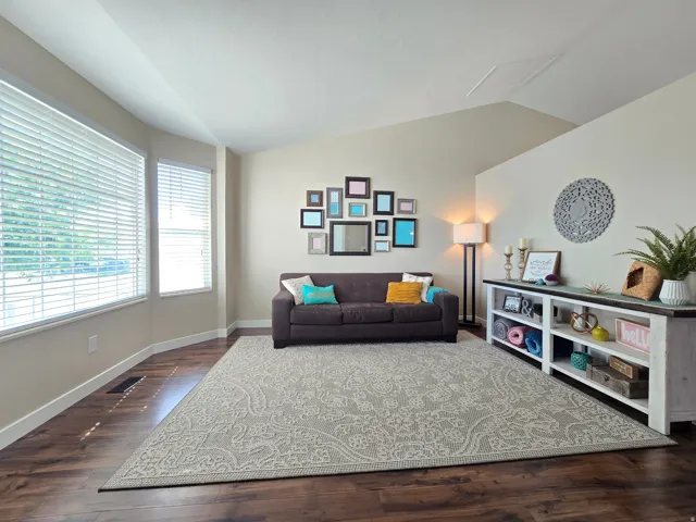 Spacious living area featuring wood-finish flooring, a neutral color palette, and abundant natural light from multiple windows