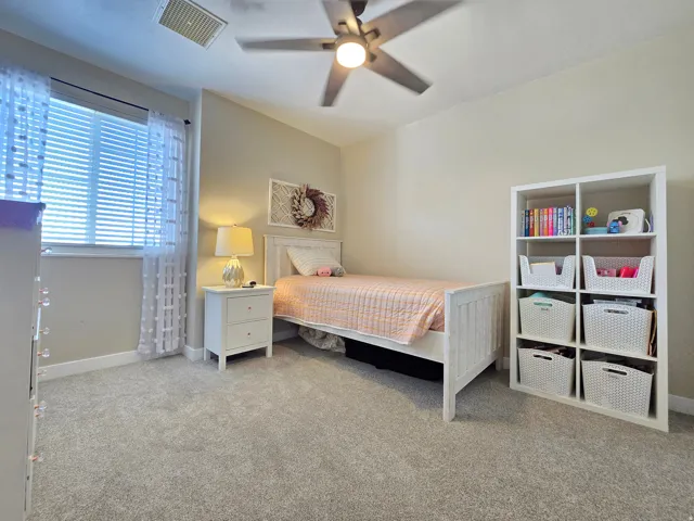 Neutral-toned room featuring a ceiling fan with integrated lighting, a window with blinds, and soft carpet flooring