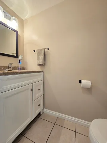 Bathroom vanity featuring a light-toned countertop, white cabinetry with silver hardware, and a framed mirror