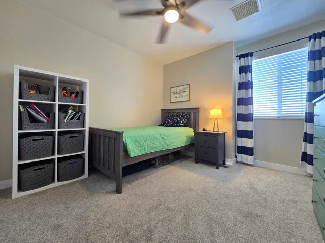 Carpeted room with a ceiling fan, window with blinds, and white baseboards