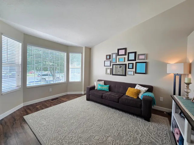 Bay window with multiple panels, wood-finish flooring, and a vaulted ceiling